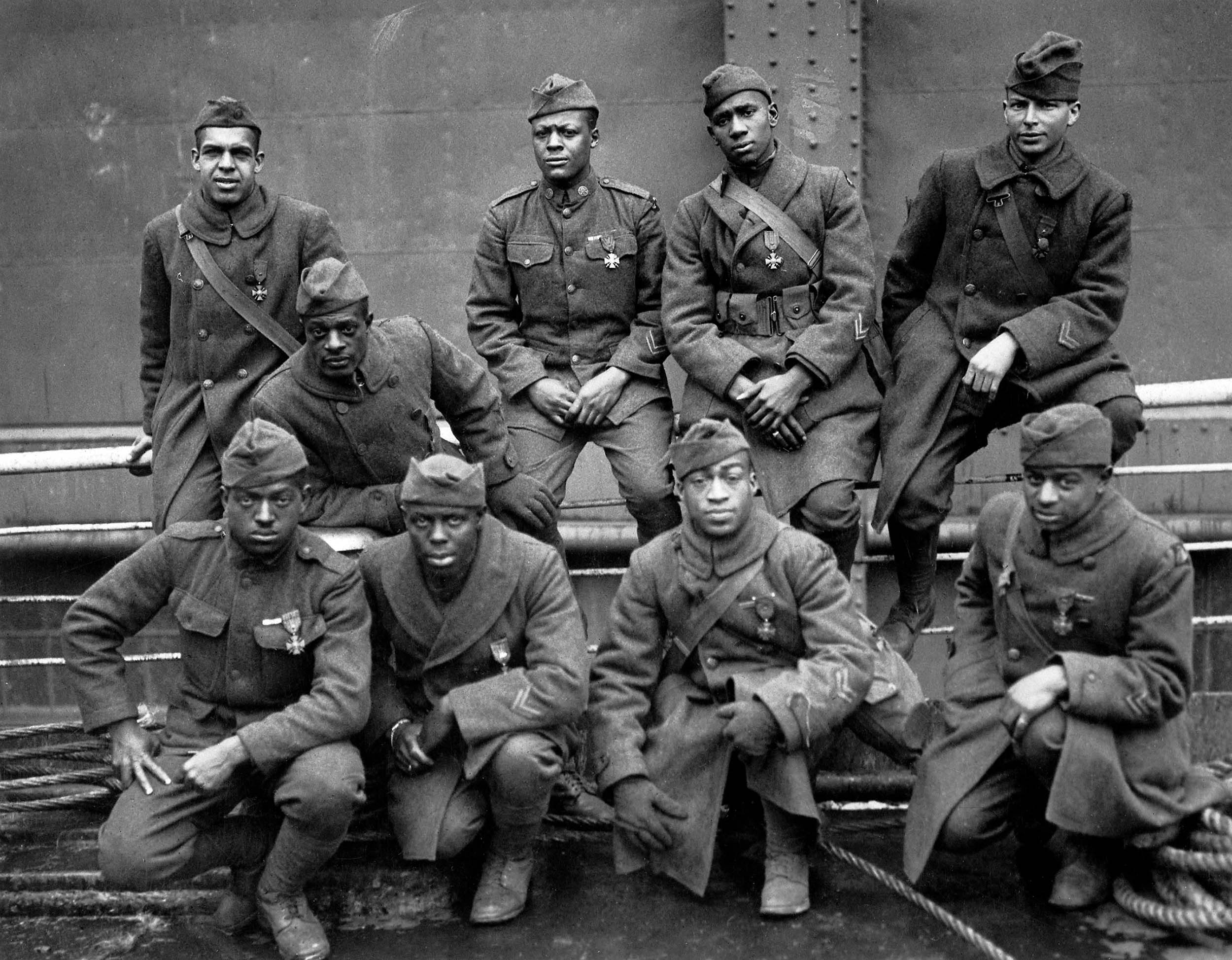 On USS Stockholm, nine Soldiers of 369th Infantry Regiment, awarded French government’s Croix de Guerre for gallantry in action, pose for photo while awaiting disembarkation in New York City, February 12, 1919; left to right, front row, Private Ed Williams, Private Herbert Taylor, Private Leon E. Fraiter, Private Ralph Hawkins; back row, Sergeant Henry David Primas, Sr., Sergeant Daniel W. Storms, Jr., Private Joe Williams, Private Alfred S. Manley, and Corporal Tyler W. Taylor (U.S. National Archives and Records Administration)
