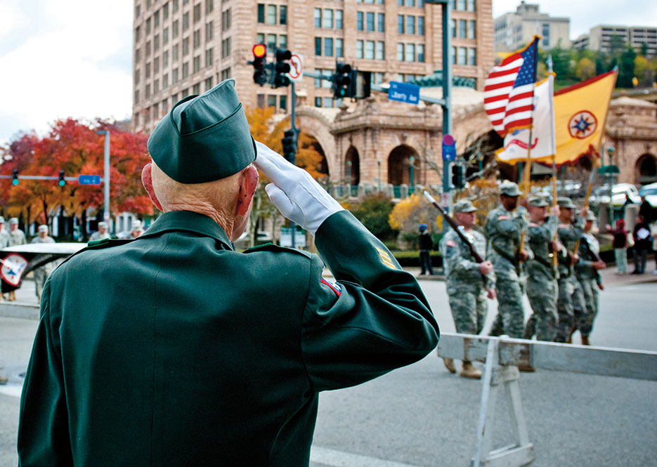 Retired Army 1st Sgt. William Staude of Elliott, Pennsylvania, salutes Soldiers from 316th Expeditionary Sustainment Command stationed in Coraopolis, Pennsylvania, as they march past him during Veterans Day parade in downtown Pittsburgh, November 2011 (U.S. Army/Michael Sauret)