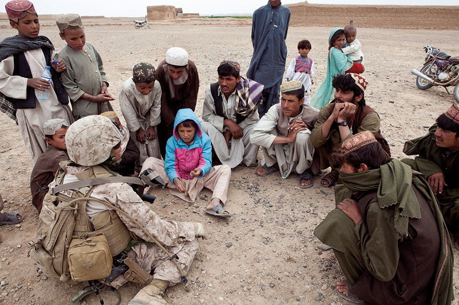 Afghan children gather around FET member during shura to discuss current local issues (U.S. Marine Corps/Andrea M. Olguin)