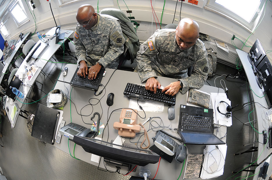 Master Sergeant Charlie Sanders (left) and Captain Lashon Bush work on Mission Event Synchronization List in Joint Cyber Control Center during Operation Deuce Lightning, Grafenwoehr, Germany, February 2011 (U.S. Army/Lawrence Torres III)