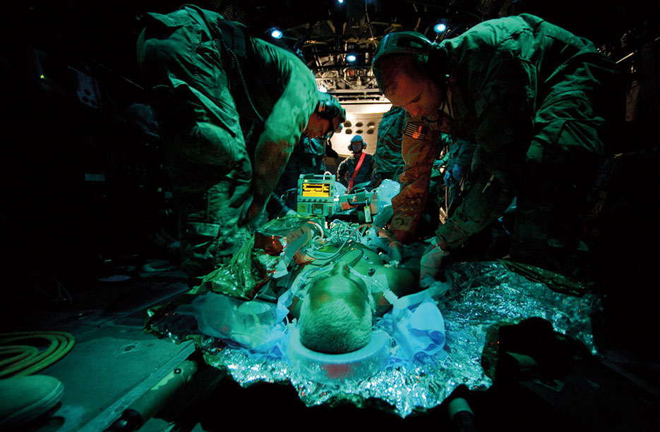 Aeromedical evacuation technician with 651<sup>st</sup> Expeditionary Aeromedical Evacuation Squadron checks on Afghan man in critical but stable condition for transport, Forward Operating Base Tarin Kowt, Afghanistan (U.S. Air Force/Greg Biondo)