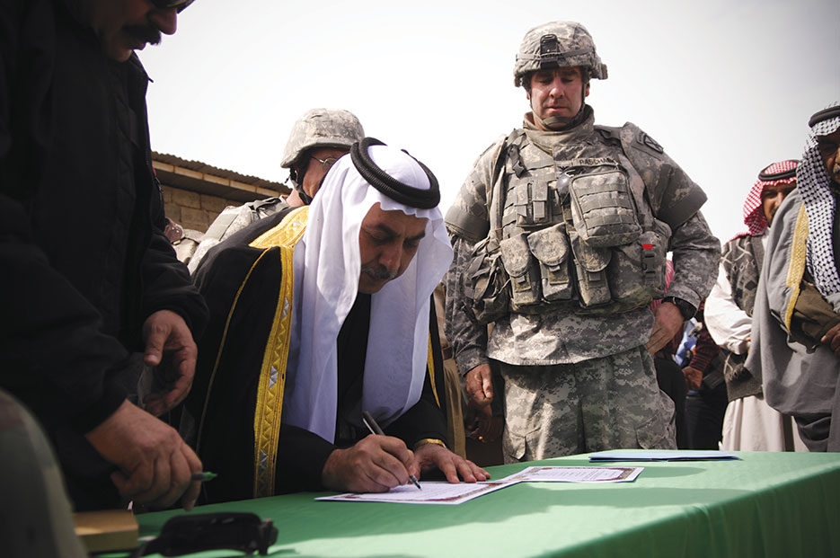 Sheik Abdullah Sami Obeidi, a Sunni Arab tribal leader, signs declaration of support for Sons of Iraq program as U.S. Army Colonel David Paschel, commander of 1st Brigade Combat Team, 10th Mountain Division, looks on in Al Noor, Iraq, March 9, 2008 (DOD/Samuel Bendet)
