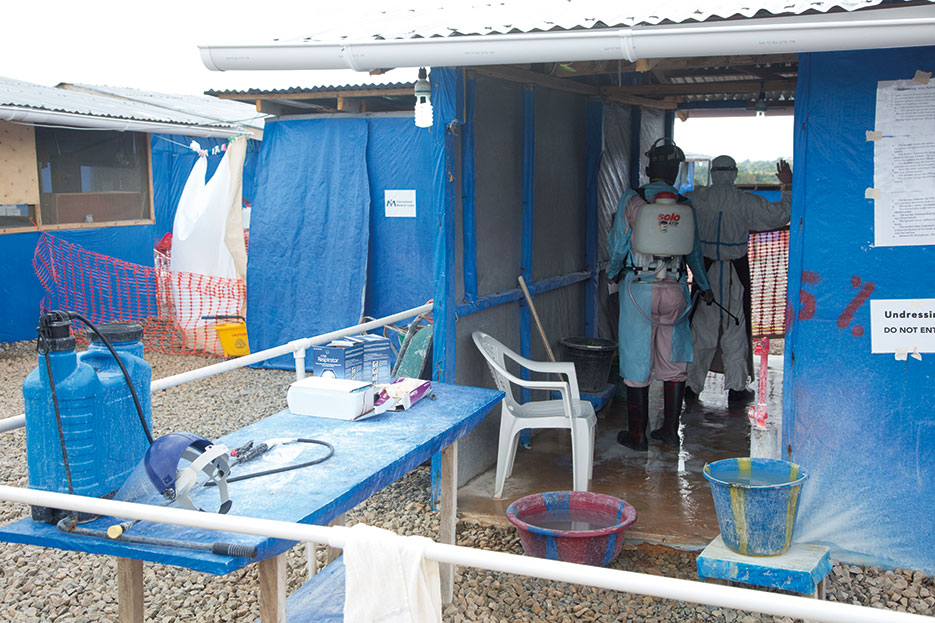 Worker decontaminates caregiver leaving patient area of active Ebola treatment center built as part of Operation United Assistance in Suakoko, Liberia, November 22, 2014 (U.S. Army/Brien Vorhees)