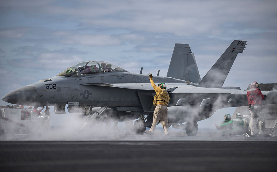 Chief Warrant Officer 3 signals to E/A-18G Growler on flight deck of aircraft carrier USS Dwight D. Eisenhower, April 11, 2016 (U.S. Navy/J. Alexander Delgado)