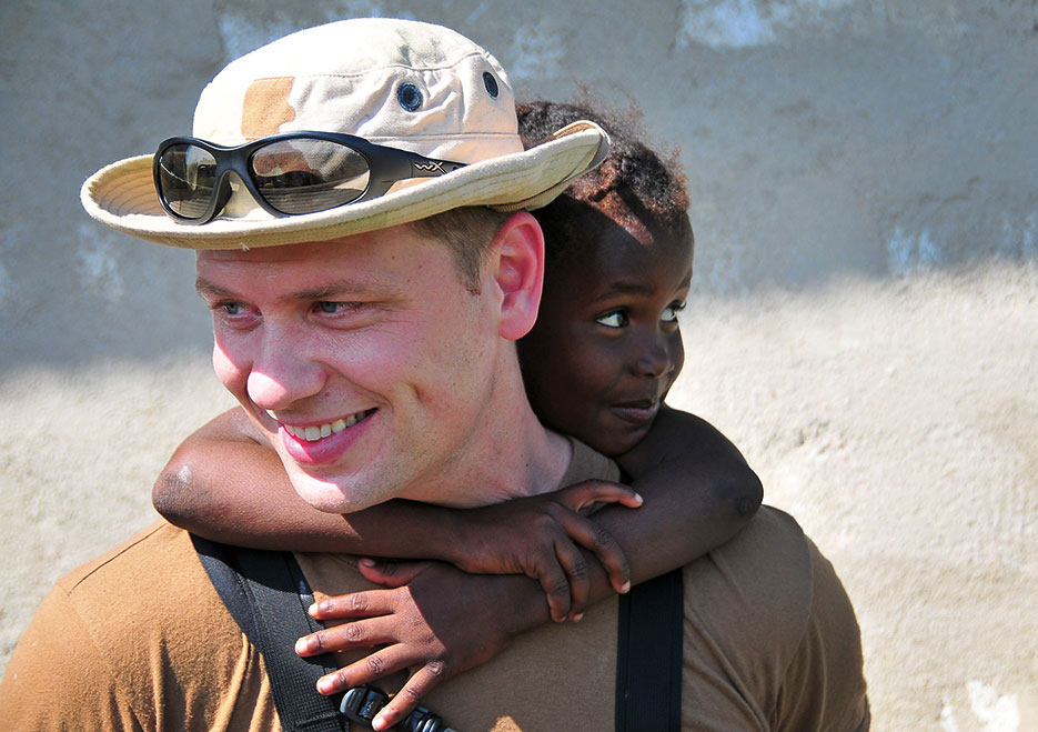 Sailor assigned to guided-missile cruiser USS Normandy carries Haitian child during site assessment as part of Operation Unified Response following 7.0 magnitude earthquake in Haiti, January 12, 2010 (DOD)