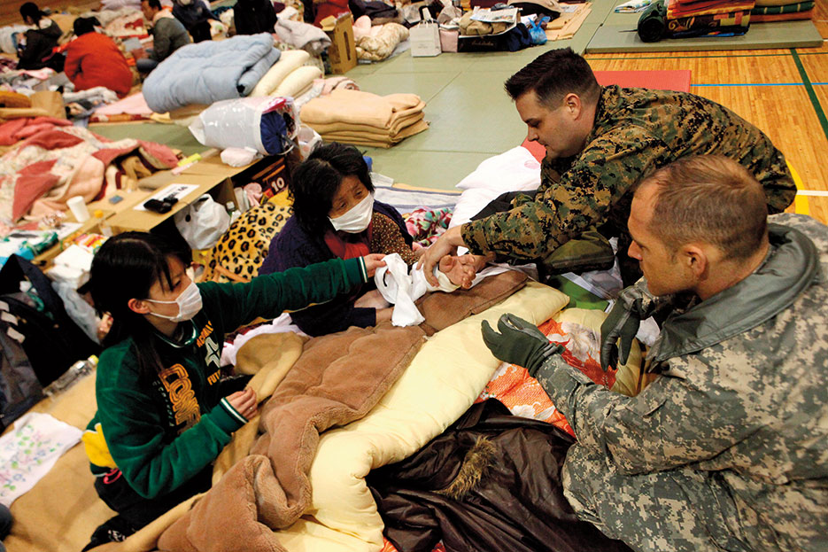 As part of Operation Tomodachi, U.S. Navy physician with III Marine Expeditionary Force (Forward) examines Japanese woman in school being used as internally displaced persons camp for residents affected by earthquake and tsunami that struck mainland Japan, March 11, 2011 (DOD)