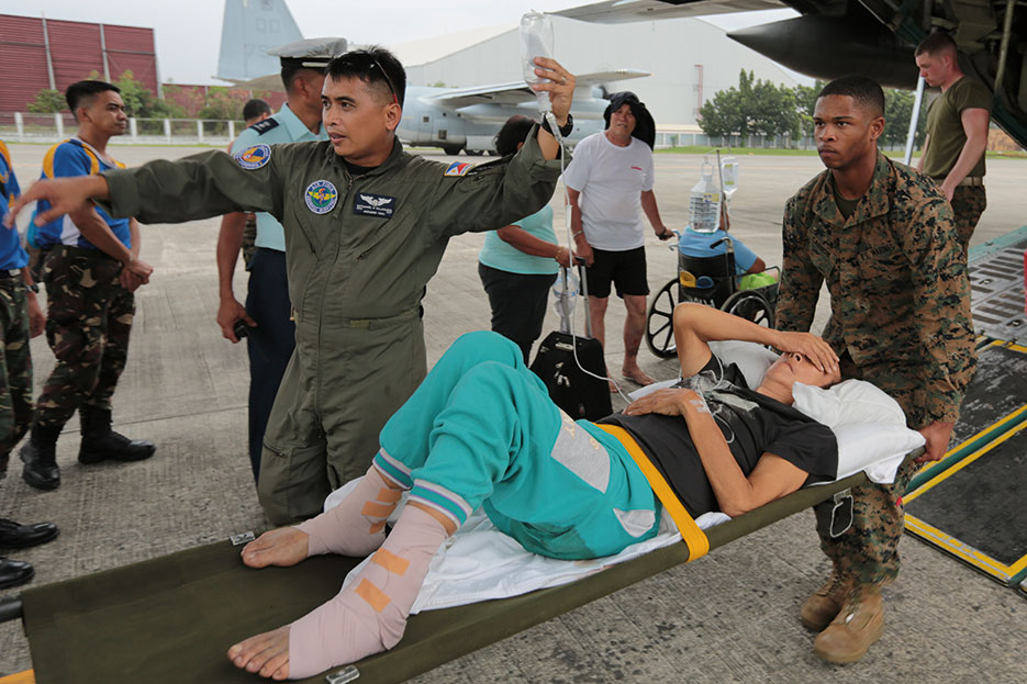 Marines carry injured Filipino woman on stretcher for medical attention at Villamor Air Base, Philippines, November 11, 2013 (DOD/Caleb Hoover)