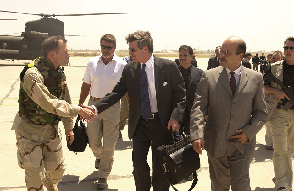 Before making his final departure from Iraq on June 28, 2004, Ambassador L. Paul Bremer shakes hands with U.S. Servicemember while he and Iraqi Deputy Prime Minister Barham Saleh walk to Baghdad International Airport (U.S. Air Force/D. Myles Cullen)
