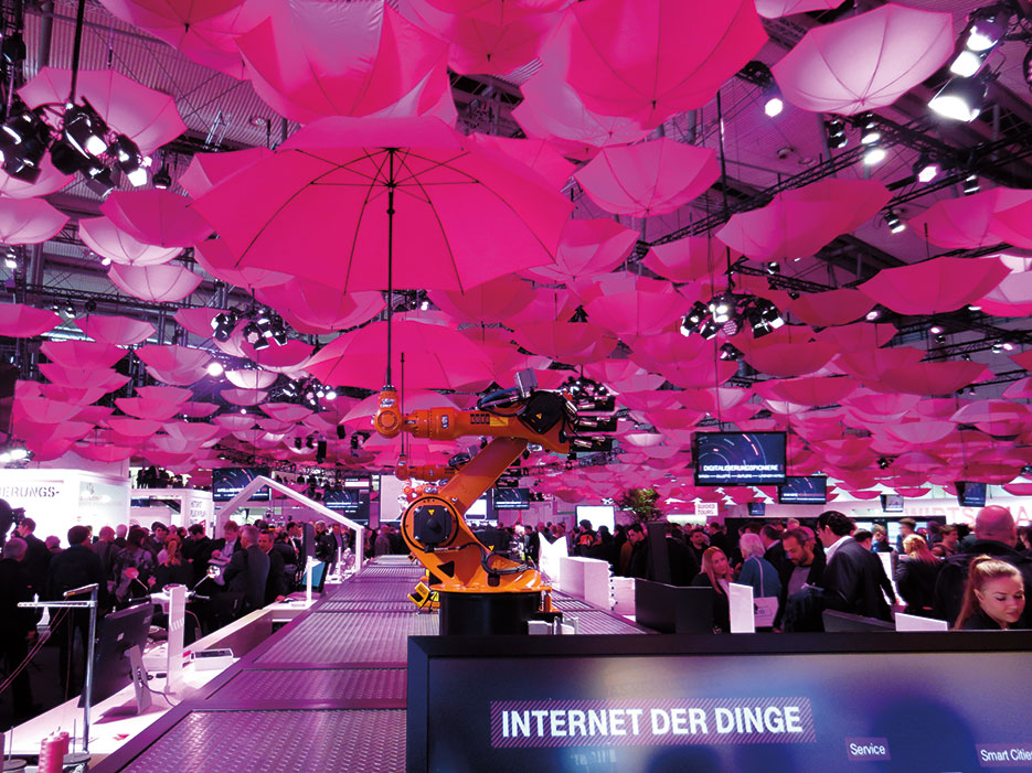 As part of Internet of Things display, booth of Deutsche Telekom at CeBit 2015 shows moving arms of robots holding magenta umbrellas, March 16, 2015 (Courtesy Mummelgrummel)