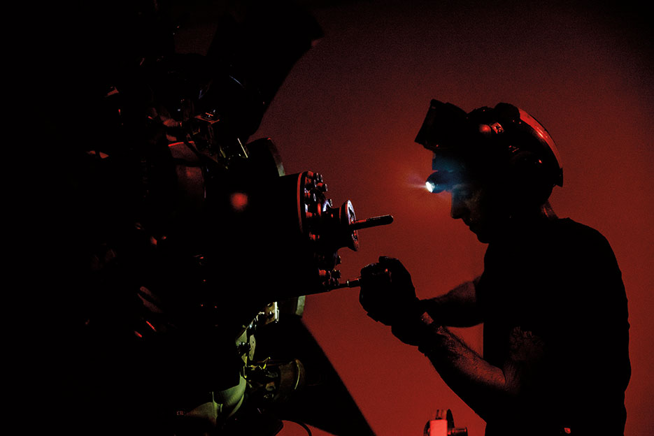 Sailor in hangar bay of aircraft carrier USS Dwight D. Eisenhower maintains E2-C Hawkeye assigned to the Screwtops of Airborne Early Warning Squadron 123, October 10, 2016 (U.S. Navy/Joshua Murray)