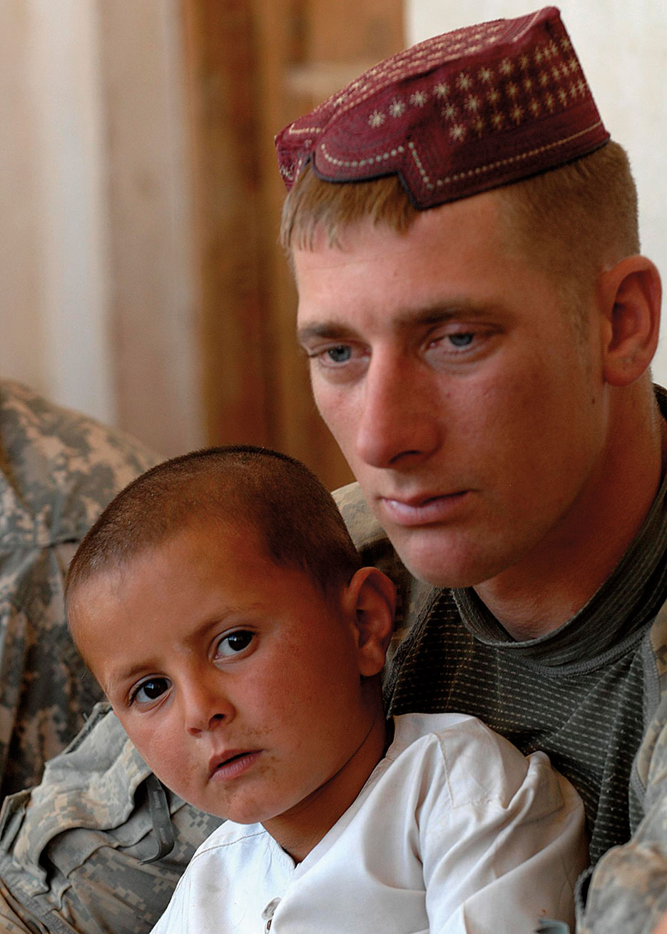 Soldier holds Afghan child and wears Kandahari hat to show solidarity during key leader meeting in Koshab Village near Kandahar Air Field, Afghanistan (U.S. Army/Stephen Schester)