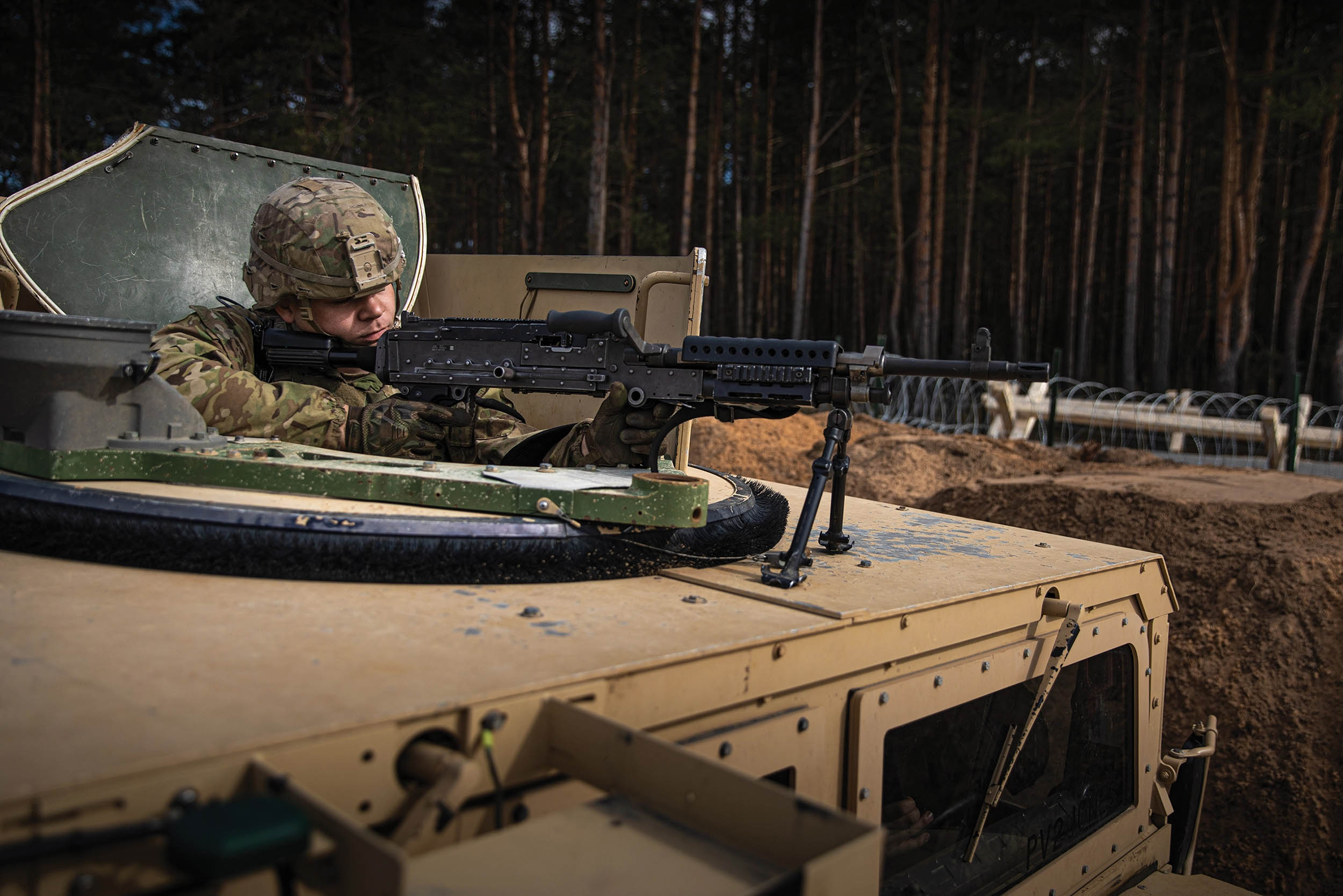 Soldier assigned to Force Protection Platoon, 3rd Battalion, 66th Armored Regiment, 1st Armored Brigade Combat Team, 1st Infantry Division, maintains perimeter security from top of Humvee during gate runner exercise conducted at Camp Herkus, Lithuania, April 13, 2022 (U.S. Army National Guard/Agustín Montañez)