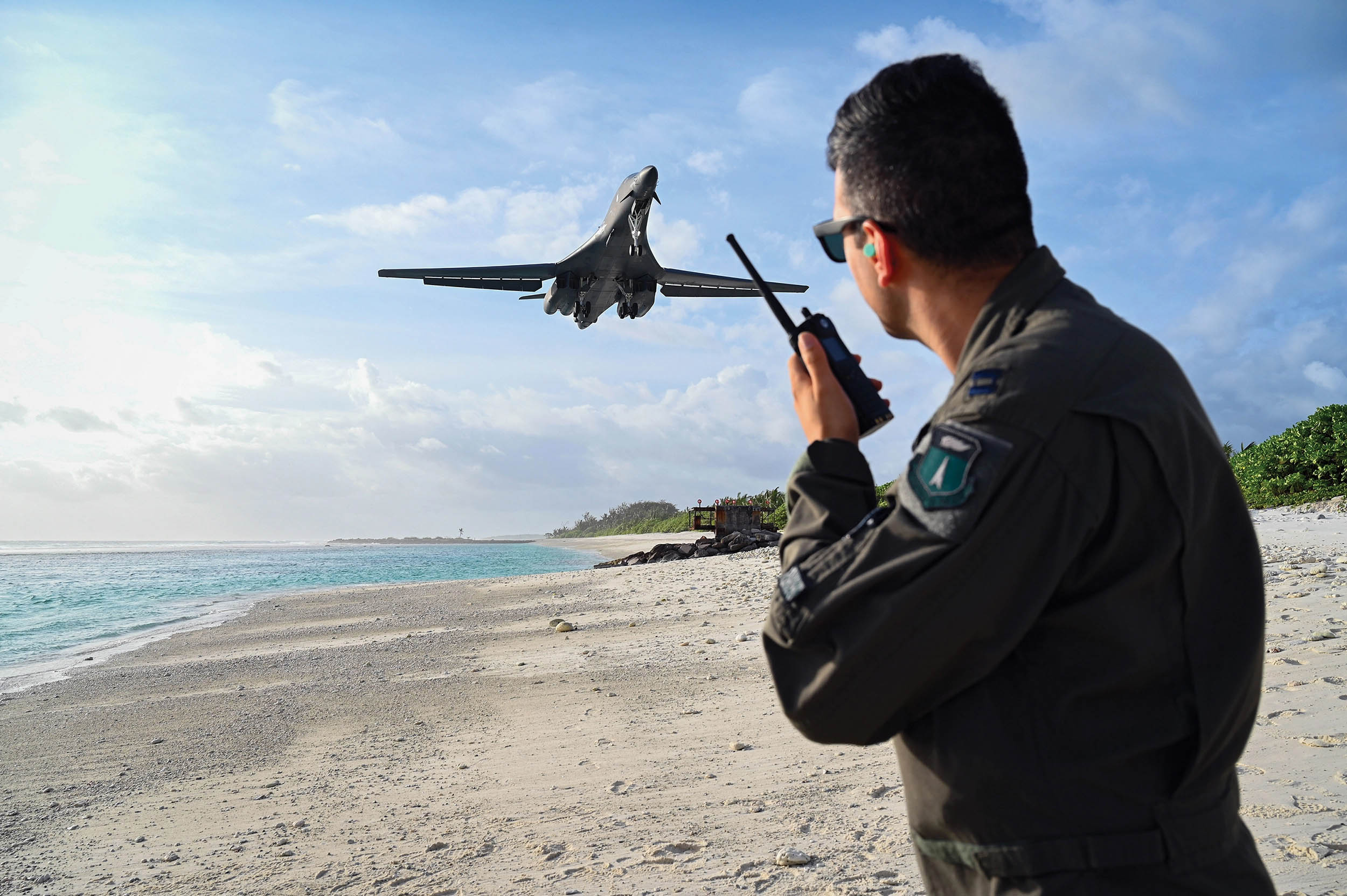 Air Force Captain Orr “Recoil” Genish, 37th Bomb Squadron weapons systems officer, uses land mobile radio as he watches B-1B Lancer land in support of Bomber Task Force mission at Naval Support Facility Diego Garcia, October 17, 2021 (U.S. Air Force/Hannah Malone)