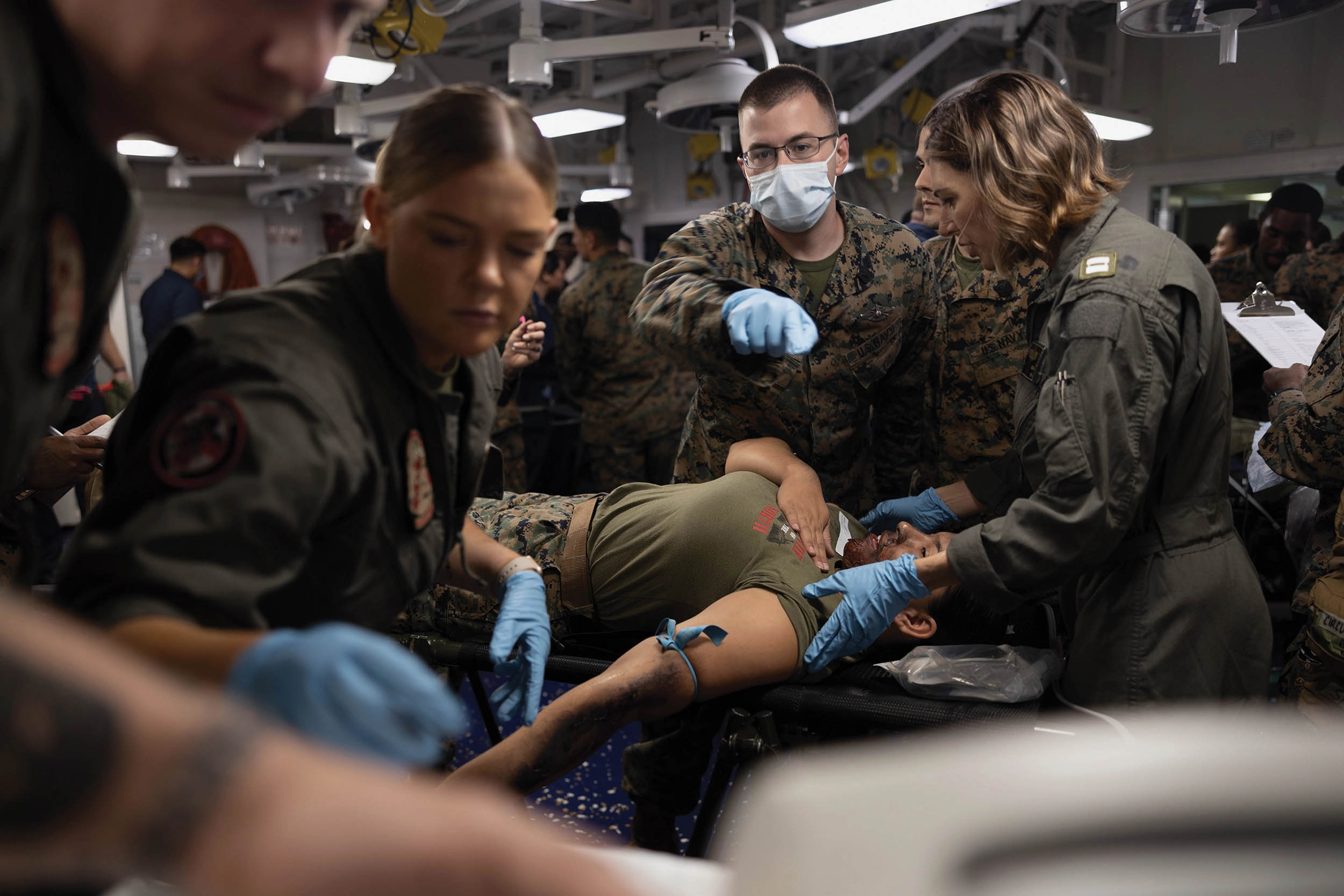 Navy Hospital Corpsman Second Class Jeffrey Ortberg, center, with Marine Medium Tiltrotor Squadron 265 (Reinforced), 31st Marine Expeditionary Unit, asks for assistance on simulated casualty during mass casualty exercise aboard amphibious assault ship USS America, Pacific Ocean, June 19, 2023 (U.S. Marine Corps/Christopher R. Lape)