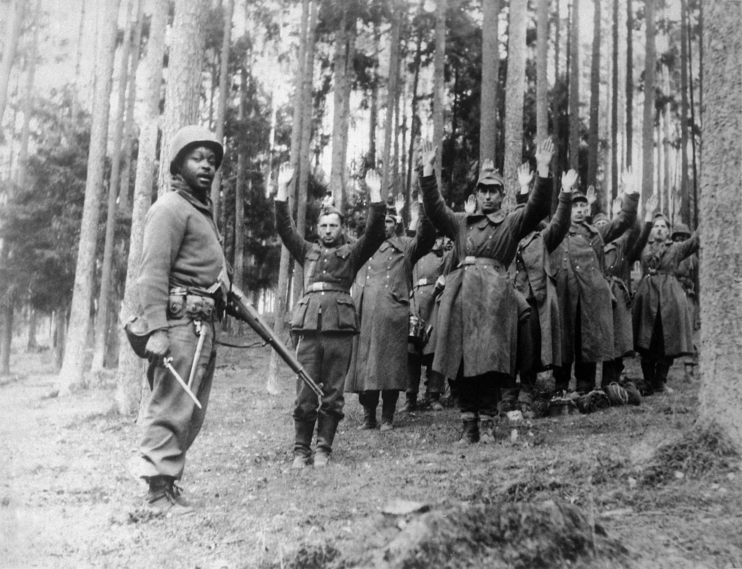 Soldier with 12th Armored Division stands guard over group of Nazi prisoners, April 1945 (National Archives and Records Administration)
