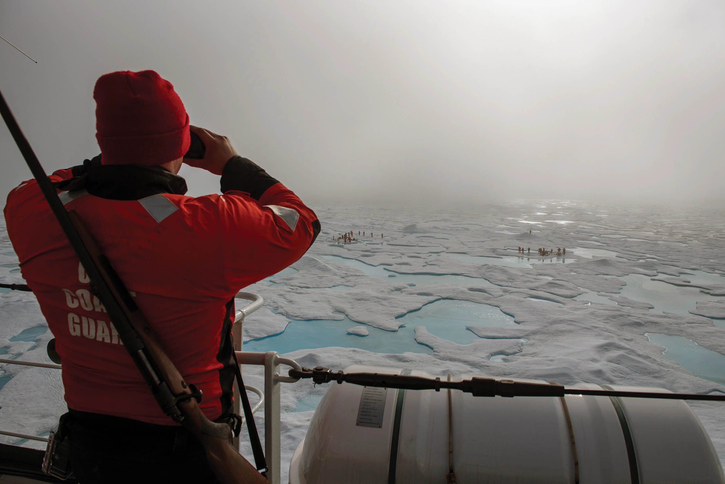 USCGC Healy crewmember Petty Officer 2nd Class Patrick Edge stands bear watch from bridge wing during on-ice science equipment installation in Beaufort Sea, August 12, 2023 (U.S. Coast Guard/Briana Carter)