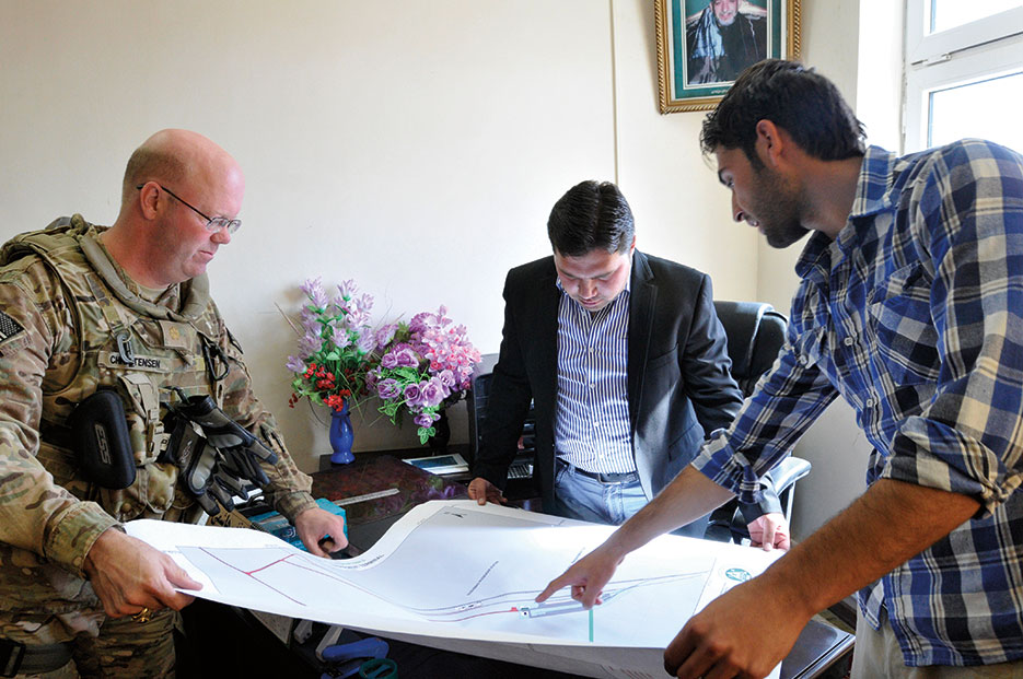Theater Sustainment Command officer of Afghan rail advisory team, deputy director of Rail Port 4, and Afghan interpreter discuss existing Rail Port 4 infrastructure on map developed by Transportation Engineering Agency, part of Surface Deployment Distribution Command (U.S. Army/Timothy Lawn)