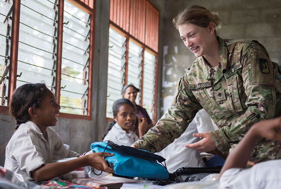 Soldier assigned to USNS Mercy hands out basic hygiene kits to local Timorese children at Dona Ana Lemos Escuela elementary school in Gleno during Pacific Partnership 2016 health outreach event, June 15, 2016 (U.S. Navy/William Cousins)